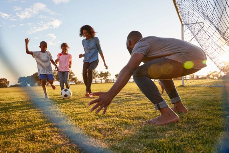 Family playing soccer outside 